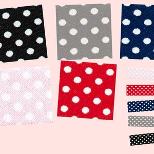 Op de afbeelding: Assortiment van stofstalen met witte stippen op verschillende gekleurde achtergronden. De kleuren omvatten zwart, grijs, marineblauw, roze, rood en wit.