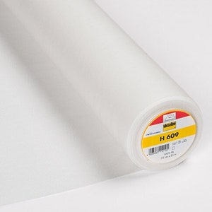 Peut inclure: Un rouleau de tissu blanc, probablement pour la couture ou l'artisanat. Le tissu est enroulé serré et semble être un matériau léger. L'étiquette sur le rouleau porte le texte "H 609".