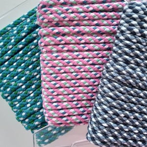 Può includere: Primo piano di tre bobine di corda decorativa in verde acqua, rosa e blu navy. La corda verde acqua ha accenti bianchi e verdi, la rosa ha accenti bianchi e blu e il blu navy ha accenti bianchi e grigi. La corda è ben avvolta e sembra resistente.