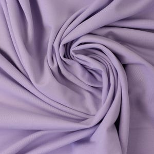 Może przedstawiać: Zbliżenie miękkiej, gładkiej tkaniny w kolorze lawendowym. Tkanina jest złożona i udrapowana, co pokazuje jej fakturę i kolor.
