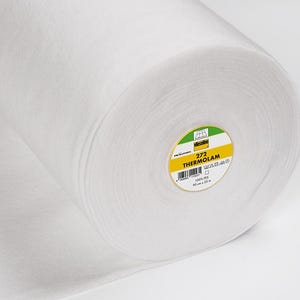 Puede incluir: Un rollo blanco de entretela 272 Thermolan. La etiqueta dice "272 Thermolan 100% PES 90 cm x 25 m".