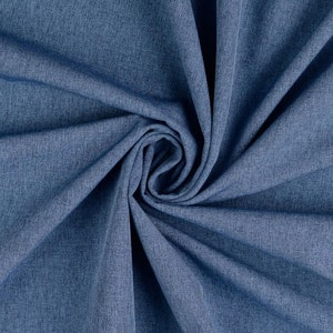 Op de afbeelding: Close-up van een blauwe stofstaal met een getextureerd oppervlak. De stof is in zachte plooien gedrapeerd, waardoor een wervelend patroon ontstaat. De kleur is een middentint blauw, met subtiele tintvariaties.
