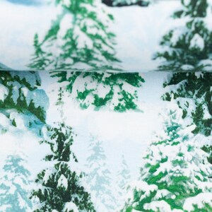 以下が含まれることがあります： 白い生地に、白い雪で覆われた緑色の松の木が繰り返しパターンで描かれています。生地は柔らかく、質感があります。