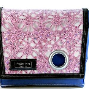 Könnte beinhalten: Eine blaue Messenger-Tasche mit einem pinkfarbenen und weißen Perlenmuster. Die Tasche hat einen schwarzen Riemen und eine silberne Öse. Die Tasche hat ein Etikett mit der Aufschrift "Pelle Mia Berlin".