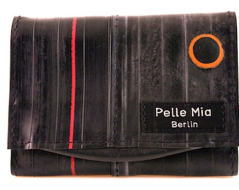 May include: A black leather wallet with a red stripe and a circular orange design. The wallet has a label that reads "Pelle Mia Berlin".