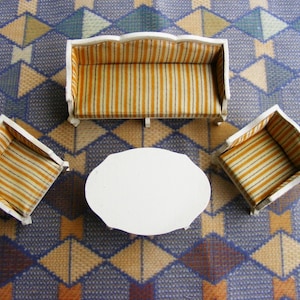 May include: A white, three-piece living room furniture set with a sofa, two armchairs, and a coffee table. The sofa and armchairs have a yellow and white striped fabric upholstery. The coffee table is round and white.