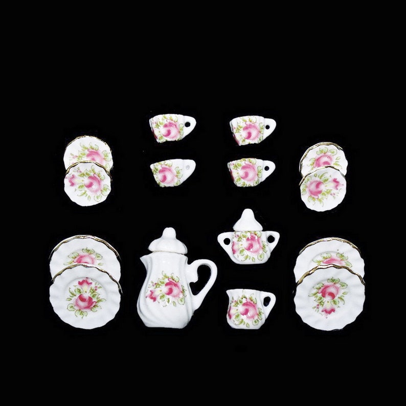 May include: A miniature tea set with a white teapot, sugar bowl, creamer, and four cups and saucers. The set features a floral design with pink roses and green leaves.