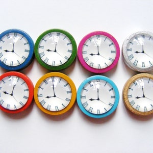 May include: Eight miniature clocks with Roman numeral faces and black hands. The clocks are in various colors: blue, green, pink, silver, red, yellow, turquoise, and gold.