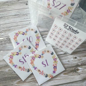 May include: A set of 52 cards with floral borders and hearts, each with a dollar amount printed on it. The cards are part of a 52-week savings challenge.