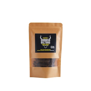 May include: A brown paper bag with a clear window showing dried meat snacks. The bag has a black label with white text that reads "Rickard's Cornish Biltong Chilli Bites 100% Prime Beef Family Kitchen Since 1989 Ready to Eat High Protein Snack Handmade in Cornwall with South West British Beef".