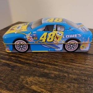 May include: A blue and yellow toy race car with the number 48 on the side. The car has a SpongeBob SquarePants design with the words "LOWE'S" on the side.