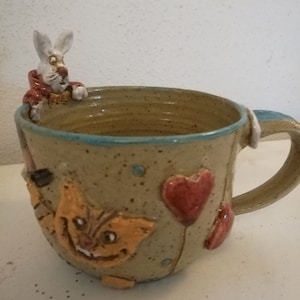 Mug with “Alice in Wonderland” motifs and a sculpted rabbit on the rim, stoneware, unique, handmade, handcrafted, exceptional