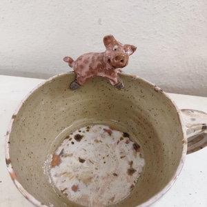 Mug artisanal en grès, orné d'un porcelet sur le bord et émaillé avec des effets de couleur. Pièce unique et originale, votre mug préféré.