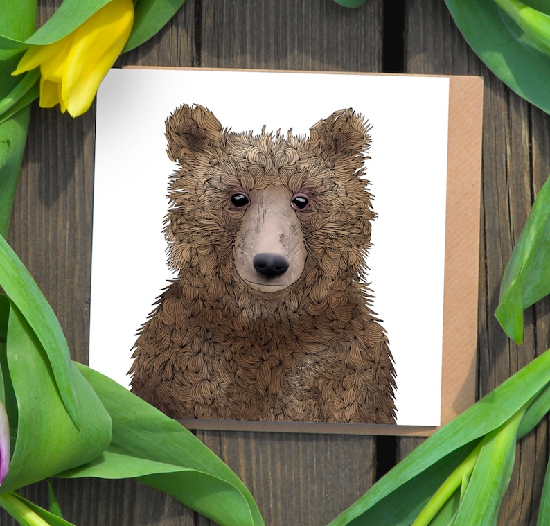 May include: A greeting card featuring a close-up illustration of a brown bear with a detailed, textured fur pattern. The bear has a friendly expression with a light brown nose and black eyes.