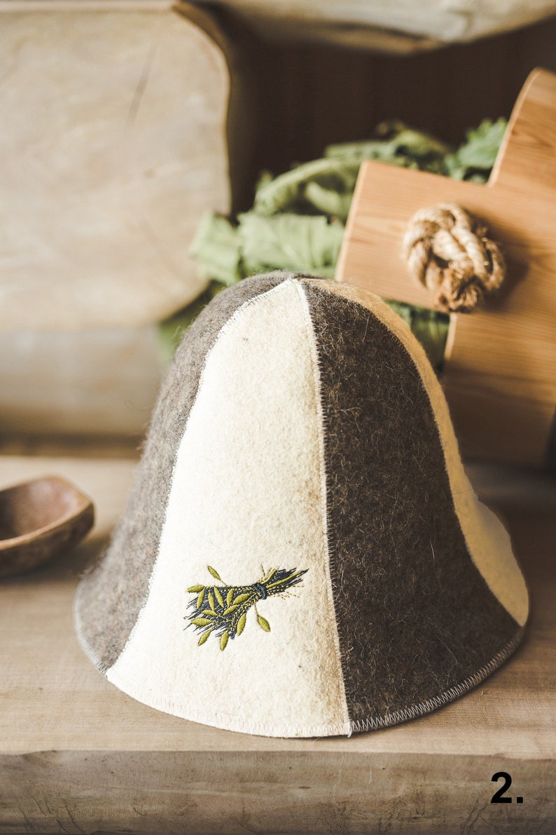 Puede incluir: Un sombrero de fieltro blanco y marr&oacute;n con un dise&ntilde;o bordado verde. El sombrero tiene una corona puntiaguda y un ala ancha.