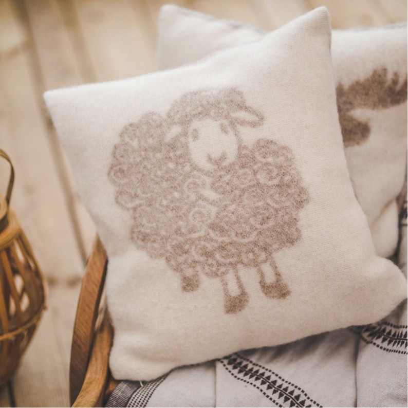May include: A white throw pillow with a brown sheep design. The pillow is made of a soft, fluffy material and is perfect for adding a touch of whimsy to any room.