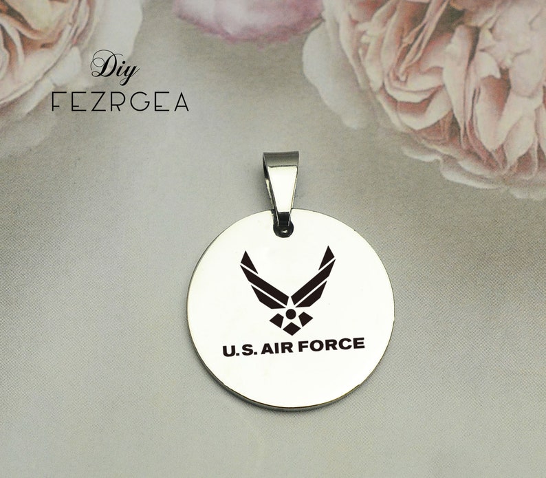 May include: A silver pendant with a black U.S. Air Force logo and the words "U.S. AIR FORCE" engraved on it.