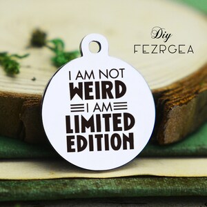 May include: A silver charm with a white background and black text that reads "I am not weird I am limited edition".