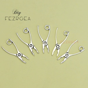 Puede incluir: Seis abalorios de alicates plateados con un bucle en la parte superior para sujetarlos a joyas u otras manualidades. Los alicates son un suministro de manualidades de bricolaje popular.