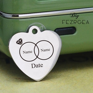 May include: Silver heart-shaped pendant with two interlocking rings and a diamond, engraved with the words "Name", "Name", and "Date".
