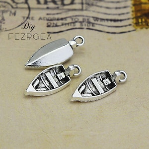 Peut inclure: Trois pendentifs en argent en forme de bateaux. Deux des pendentifs ont un motif rayé et un est une forme simple et pointue.