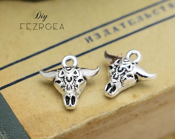 May include: Two silver bull head charms with intricate designs. The charms have a loop at the top for attaching to jewelry or other crafts.