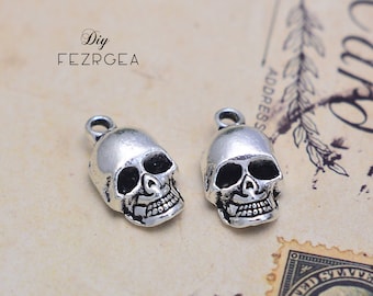 May include: Two silver skull charms with detailed facial features. The charms have a loop at the top for attaching to jewelry or other crafts.