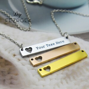 May include: A silver chain necklace with three layered bar pendants. The top bar is silver and has the text "Your Text Here" with a heart cut-out. The middle bar is rose gold and the bottom bar is gold, both with heart cut-outs.