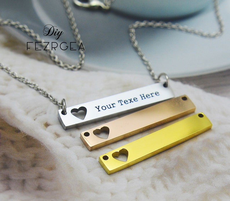 May include: A silver chain necklace with three layered bar pendants. The top bar is silver and has the text "Your Text Here" with a heart cut-out. The middle bar is rose gold and the bottom bar is gold, both with heart cut-outs.