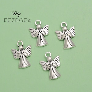 May include: Four silver-colored angel charms with detailed wings and clasped hands. Each charm has a small loop at the top for attaching to jewelry or other crafts. The background is a light green color.