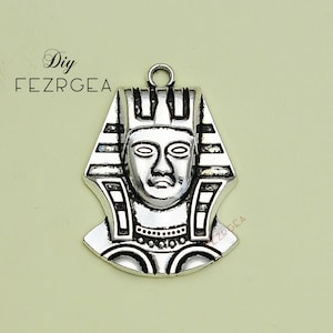 May include: Silver pendant charm featuring a detailed depiction of an Egyptian pharaoh's head wearing a traditional headdress.