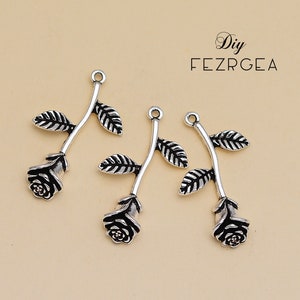 May include: Three silver-toned rose charms with black detailing. Each charm features a rose with leaves and a loop at the top for attaching to jewellery or other crafts.