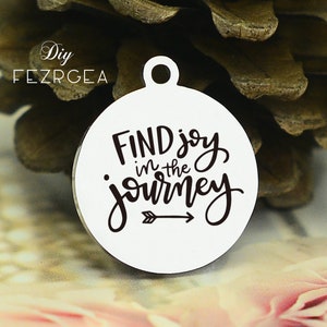 以下が含まれることがあります： 「FIND joy in the journey」というテキストと右を指す矢印が書かれた丸い銀色のチャームです。