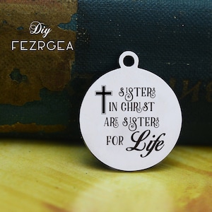 May include: A silver charm with a cross and the text "Sisters in Christ are sisters for life".