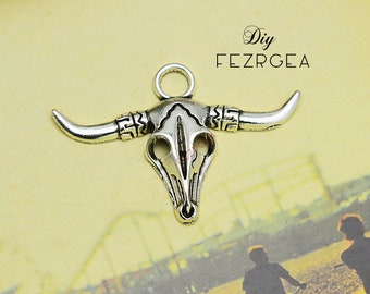 May include: Silver-toned metal bull skull charm with a loop at the top for hanging. The skull has intricate details and a textured finish.