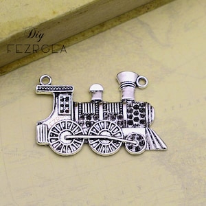 May include: Silver-toned metal train charm with a detailed design. The charm features a locomotive with wheels, a smokestack, and a bell. It is a great addition to jewelry making or crafting projects.