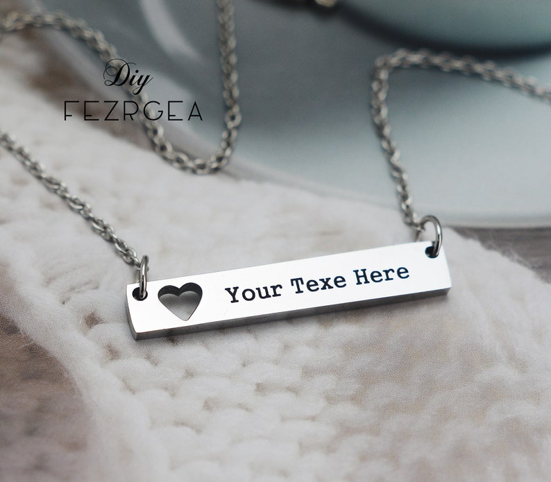 May include: A silver necklace with a bar pendant that says "Your Text Here" with a heart cut out.