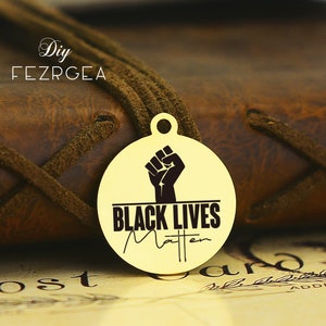 May include: Gold-colored round pendant with a black raised fist and the text "Black Lives Matter" in black lettering.