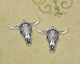 May include: Two silver-toned bull skull charms with intricate etched designs. The charms have a loop at the top for attaching to jewelry or other crafts.