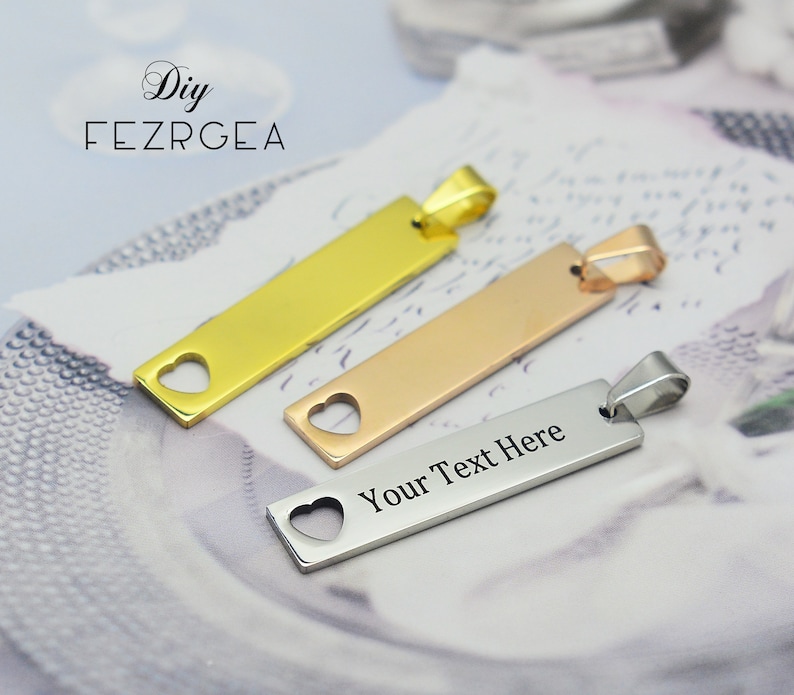 May include: Three rectangular pendants in gold, rose gold, and silver. Each pendant has a heart-shaped cutout and a loop for a chain. The silver pendant has the text "Your Text Here".