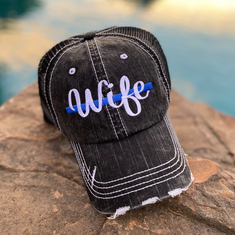 May include: Black distressed baseball cap with a white embroidered "wife" and a blue thin line across the front.