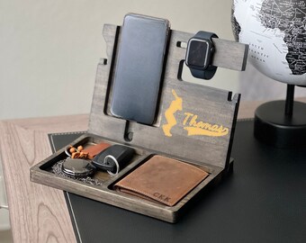May include: A wooden phone stand with a gray finish. It has a slot for a phone, a watch, and a tray for keys and a wallet. The stand is personalized with the name "Thomas" and a baseball player graphic.