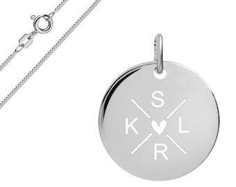 May include: A silver-toned circular pendant necklace featuring a polished finish. The pendant is engraved with the letters S, K, L, and R arranged in a cross pattern around a central heart symbol. The piece includes a delicate silver chain with a clasp.
