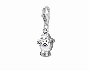 May include: A silver-colored charm in the shape of a sheep. The sheep has a white body and a black face. The charm is attached to a silver clasp.