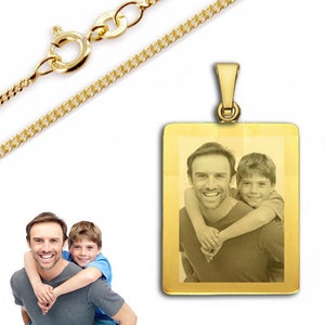 Può includere: Collana con catena d'oro con un ciondolo rettangolare che presenta una foto di un padre e un figlio. Il ciondolo ha una finitura liscia e lucida.
