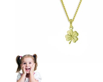 May include: A gold-colored necklace with a four-leaf clover pendant. The clover is a symbol of good luck. The necklace is on a white background. A young girl with pigtails is in the lower left corner, smiling with her hands on her cheeks.