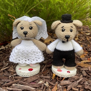 Puede incluir: Una pareja de boda de crochet, una novia y un novio, vestidos de blanco y negro, de pie sobre pequeños soportes para pasteles.
