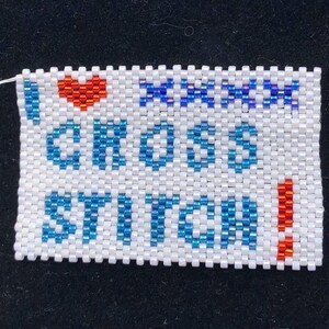 May include: White beaded bracelet with blue and red beads spelling "I love craft beer!" with a red heart bead.