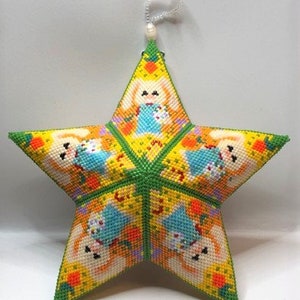 May include: A yellow, green, and orange star-shaped ornament with a beaded string hanging from the top. The ornament is decorated with a repeating pattern of bunnies holding carrots.