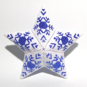 Op de afbeelding: Een witte, vijfhoekige sterversiering met een kralenstructuur. De ster is versierd met blauwe sneeuwvlokpatronen. Het ornament is waarschijnlijk voor vakantie- of seizoensdecoratie.